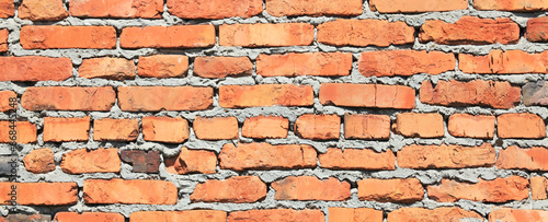 Old brick wall texture, background. The fragment of bad and dirty bricklaying with cement smeared bricks. Uneven brickwork and wall backdrop of building. Old, faded, rough wallsurface of red bricks photo