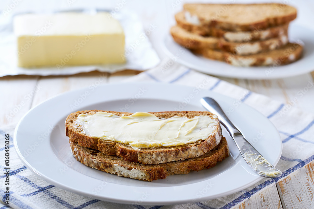 Fresh crusty buttered rye bread slices with butter on a wooden table Fresh crusty buttered rye bread slices with butter on a wooden table