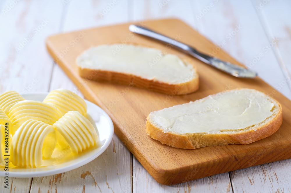 spread butter on a slice of wheat bread on a cutting board, selective focus. spread butter on a slice of wheat bread on a cutting board, selective focus.