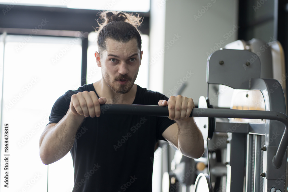Male athlete using exercise machine during strength training in gym. Man workout using exercise with machine in gym. Sport fitness concept Male athlete using exercise machine during strength training in gym. Man workout using exercise with machine in gym. Sport fitness concept