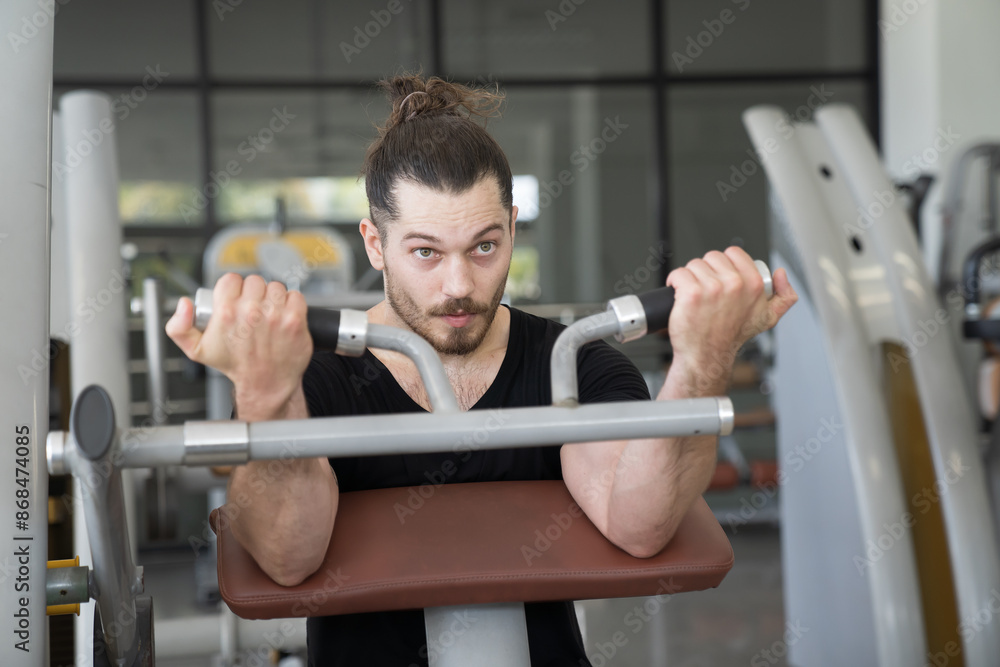 Male athlete using exercise machine during strength training in gym. Man workout using exercise with machine in gym. Sport fitness concept Male athlete using exercise machine during strength training in gym. Man workout using exercise with machine in gym. Sport fitness concept