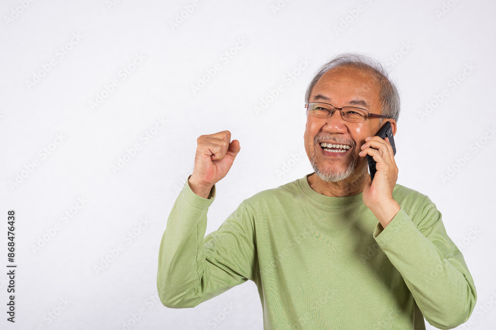 Portrait Asian smiling old man with glasses while talking on his cell phone studio shot isolated on white background, happy senior man calling to someone with mobile phone Portrait Asian smiling old man with glasses while talking on his cell phone studio shot isolated on white background, happy senior man calling to someone with mobile phone