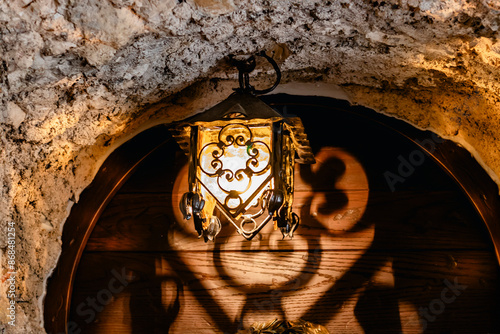 Obraz na płótnie Aged brass light fixture in a stone archway casting intricate shadows, creating vintage elegance w salonie