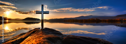 Chromed metal cross on the lake at sunset photo