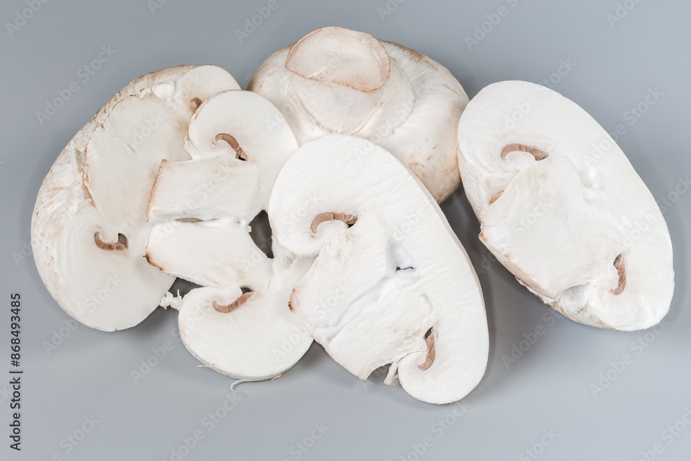 Whole and sliced fresh raw button mushrooms on gray background Whole and sliced fresh raw button mushrooms on gray background