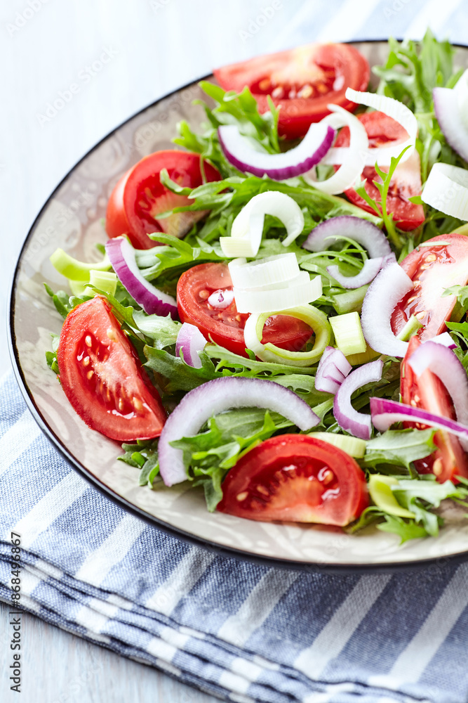 Salad with fresh tomatoes and arugula on a bright background. Close up. Salad with fresh tomatoes and arugula on a bright background. Close up.