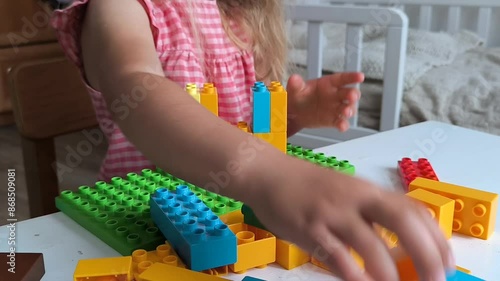 little girl plays color constructor sitting children room table