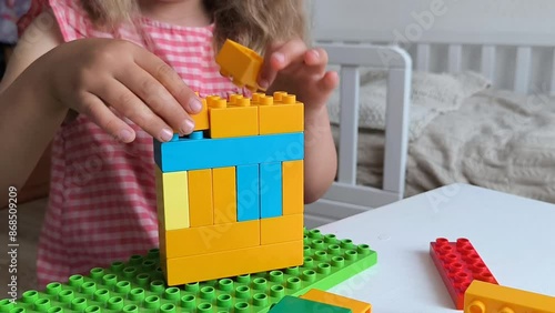 little girl plays color constructor sitting children room table