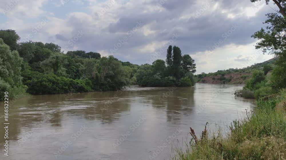 River flows along the forest against the background of a cloudy sky River flows along the forest against the background of a cloudy sky
