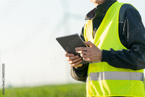 Engineer with digital tablet works on a field of wind turbines 