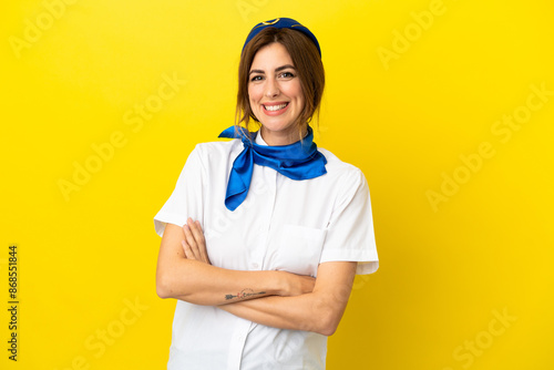 Airplane stewardess woman isolated on yellow background keeping the arms crossed in frontal position photo