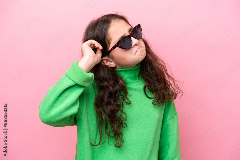 Little caucasian girl wearing sunglasses isolated on pink background having doubts and with confuse face expression Little caucasian girl wearing sunglasses isolated on pink background having doubts and with confuse face expression