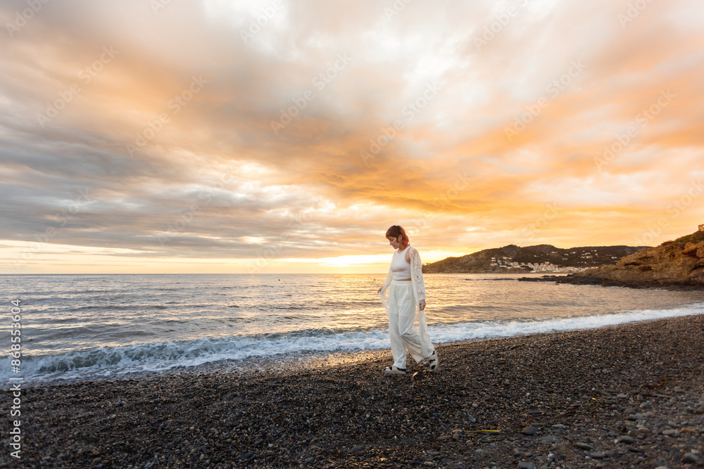 A woman is walking on a beach at sunset A woman is walking on a beach at sunset