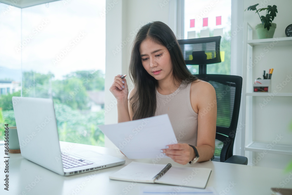 Beautiful young businesswoman working with financial reports and using laptop at her office. Beautiful young businesswoman working with financial reports and using laptop at her office.