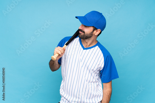 Sticker Young man playing baseball over isolated blue background laughing