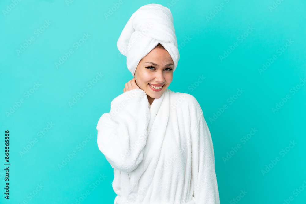 Teenager blonde girl in a bathrobe over isolated blue background laughing Teenager blonde girl in a bathrobe over isolated blue background laughing