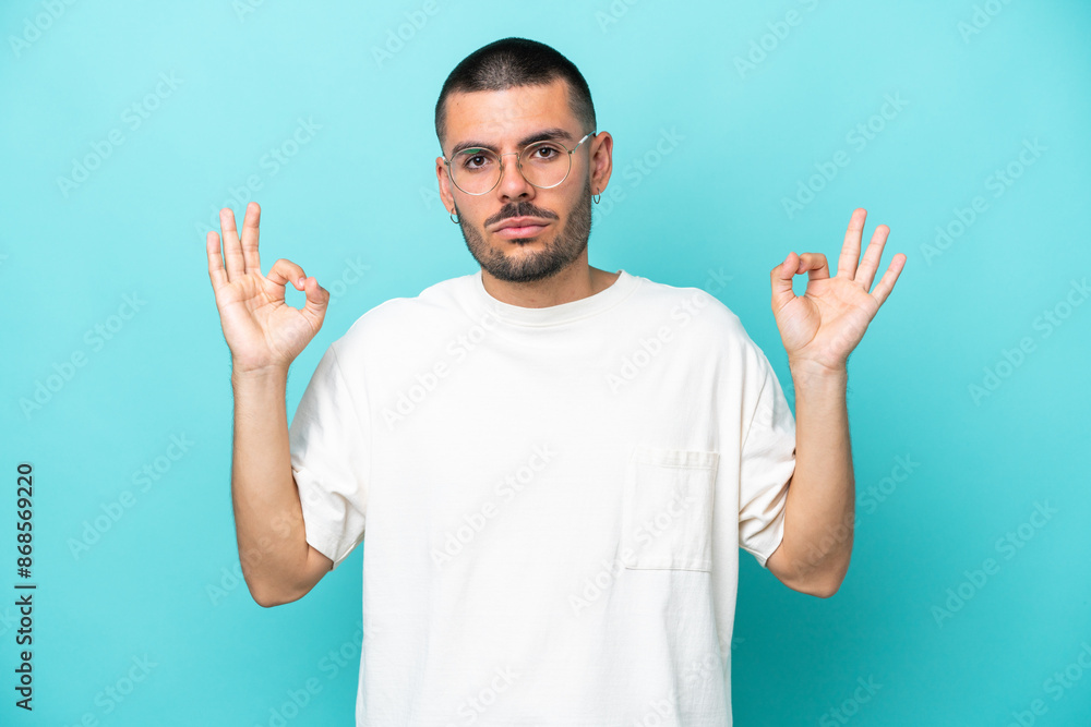 Young caucasian man isolated on blue background in zen pose Young caucasian man isolated on blue background in zen pose