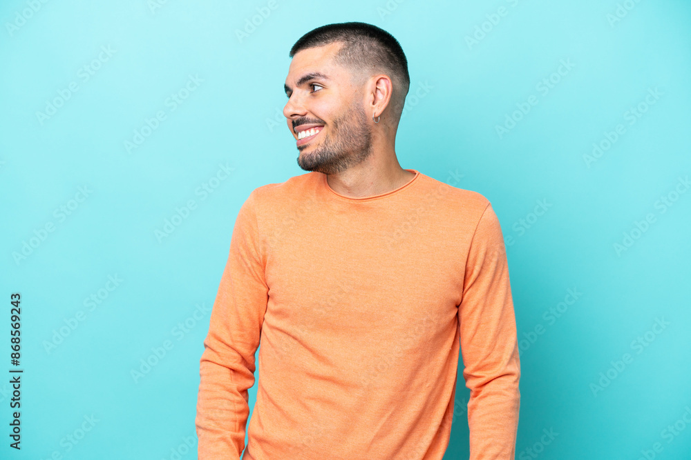 Young caucasian man isolated on blue background looking to the side and smiling Young caucasian man isolated on blue background looking to the side and smiling