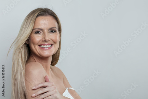 Healthy mid adult woman touching her perfect skin. Beautiful portrait mature 50s aged woman on white background.