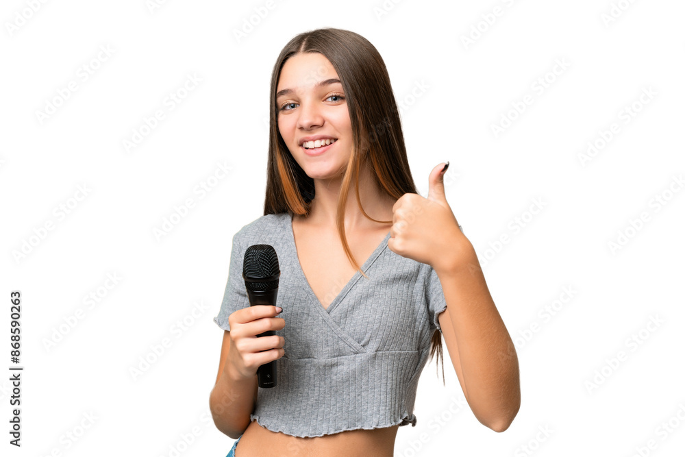 Teenager singer girl picking up a microphone over isolated background with thumbs up because something good has happened Teenager singer girl picking up a microphone over isolated background with thumbs up because something good has happened