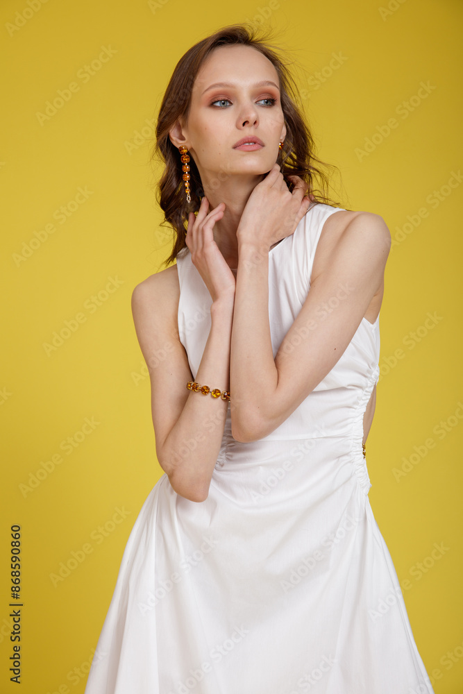High fashion photo of a beautiful skinny young woman in pretty white dress posing on yellow background. Slim figure. High fashion photo of a beautiful skinny young woman in pretty white dress posing on yellow background. Slim figure.