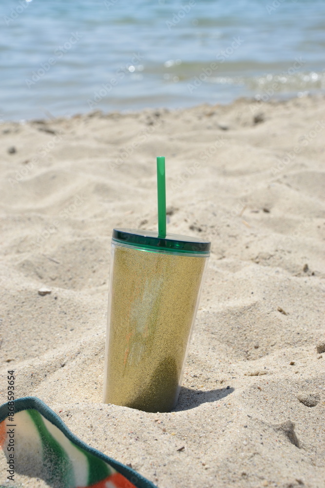 Golden sparkling cup of cold beverage at the sand beach Golden sparkling cup of cold beverage at the sand beach