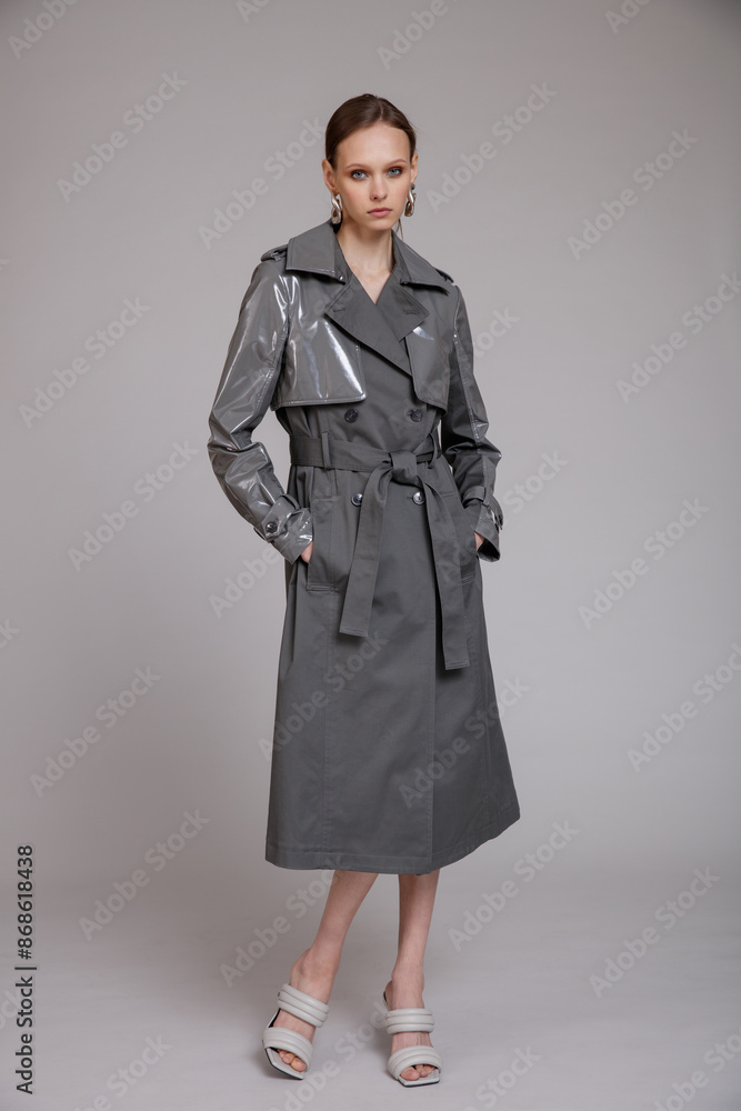 High fashion photo of a beautiful skinny young woman in pretty gray coat, jacket posing on studio background. Slim figure. monochrome High fashion photo of a beautiful skinny young woman in pretty gray coat, jacket posing on studio background. Slim figure. monochrome