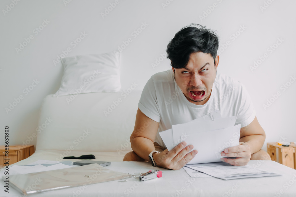 Asian man get crazy and desperate with documents problems of bills and loans. Asian man get crazy and desperate with documents problems of bills and loans.