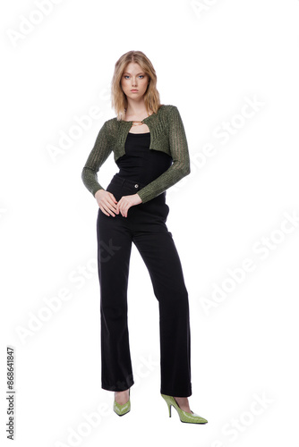 High fashion photo of a beautiful elegant young woman in pretty black denim pants, trousers, top, green short jacket posing on white background. Slim figure. Blonde