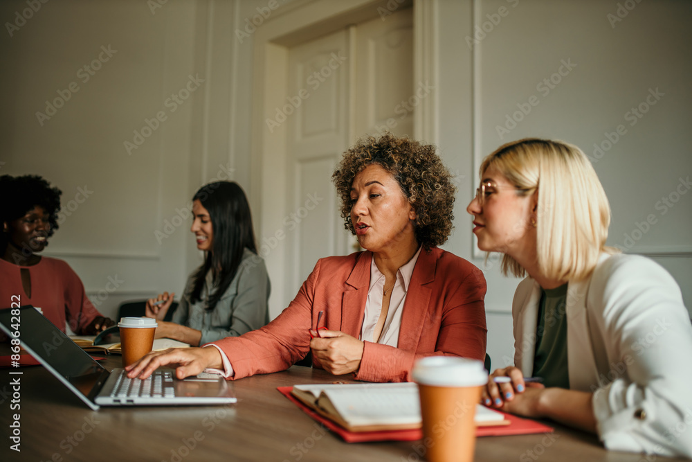 Office colleagues having casual discussion during meeting in conference room. Group of successful business women sitting in the conference room and talking Office colleagues having casual discussion during meeting in conference room. Group of successful business women sitting in the conference room and talking