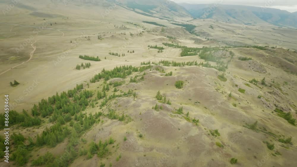 The copter flies high above the hilly desert area. Snowy mountains and rivers in the distance. The copter flies high above the hilly desert area. Snowy mountains and rivers in the distance.