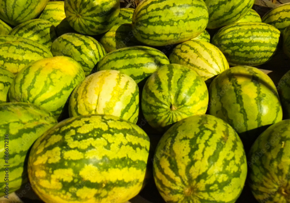 large sweet green watermelons are placed on a wooden table on a natural background for sale. large sweet green watermelons are placed on a wooden table on a natural background for sale.