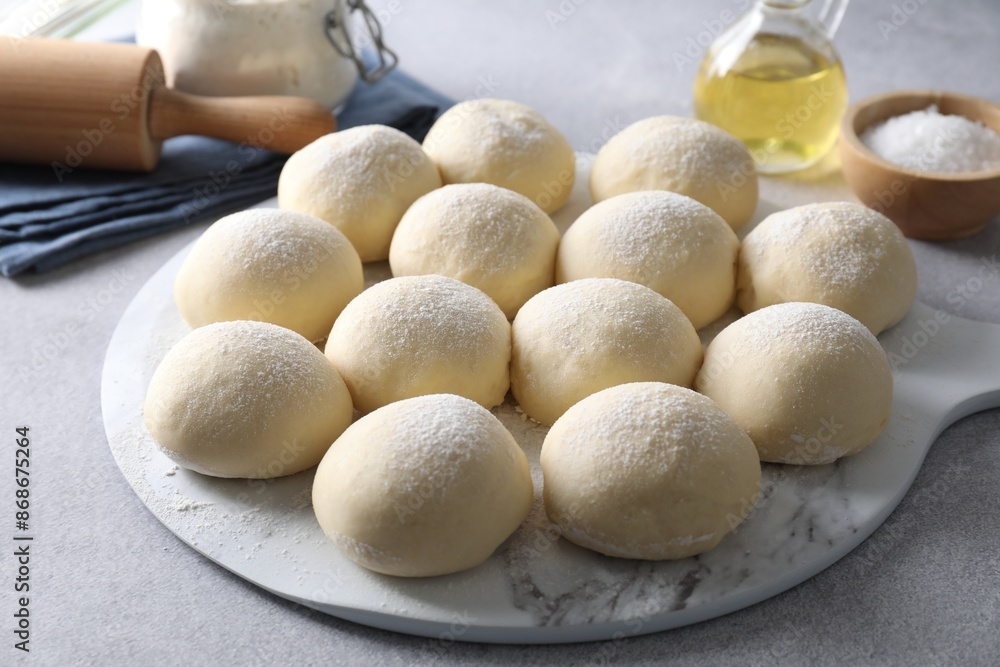 Raw dough balls, rolling pin, oil and salt on light grey table Raw dough balls, rolling pin, oil and salt on light grey table