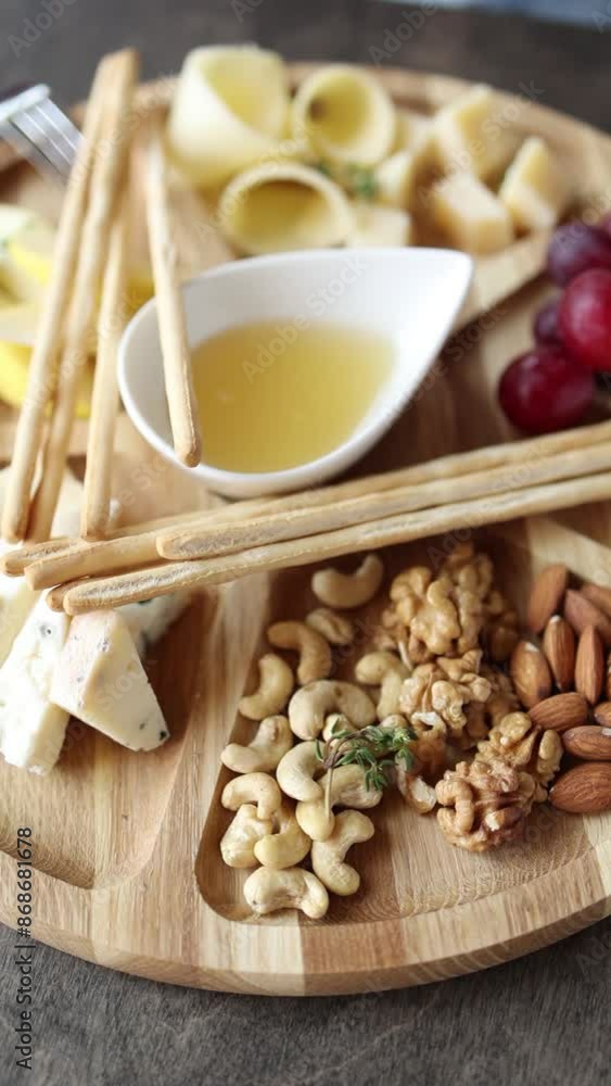 A dish of sliced hard cheese, nuts, honey, and grapes. Close up A dish of sliced hard cheese, nuts, honey, and grapes. Close up