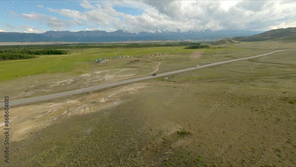 FPV drone will fly low above the ground near a young girl. The girl goes hiking in the mountains, climbs to the top. Cloudy weather, snowy mountains in the background. FPV drone will fly low above the ground near a young girl. The girl goes hiking in the mountains, climbs to the top. Cloudy weather, snowy mountains in the background.