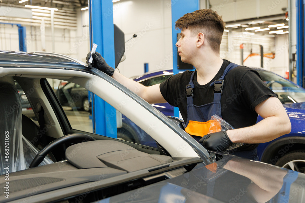 Warranty case for windshield replacement at a car service center. Mechanic makes marks before replacing glass Warranty case for windshield replacement at a car service center. Mechanic makes marks before replacing glass