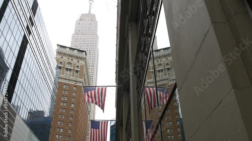 New York, american flag waving. Empire State Building. Manhattan midtown city street, Broadway. Symbol of freedom, democracy, liberty and patriotism. Star-Spangled Banner, Old Glory. Stars and Stripes