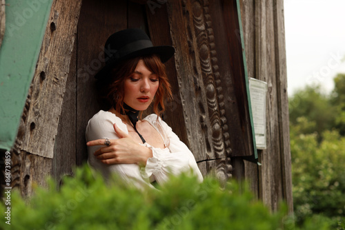 Beautiful woman in vintage dress and hat standing at old wooden door #868739859