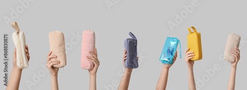 Many hands holding school pencil cases on light background photo