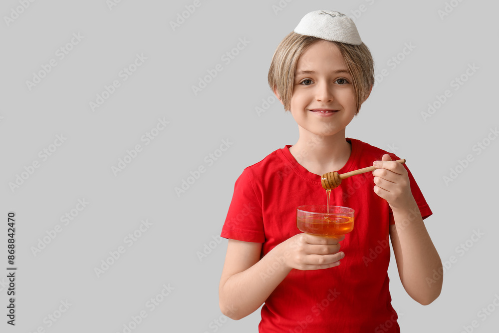 Cute little boy holding bowl with honey on grey background. Rosh Hashanah (Jewish New Year) celebration Cute little boy holding bowl with honey on grey background. Rosh Hashanah (Jewish New Year) celebration