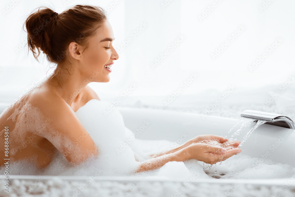 Pretty Woman Filling Bath With Water, Checking Temperature, Copy Space Pretty Woman Filling Bath With Water, Checking Temperature, Copy Space