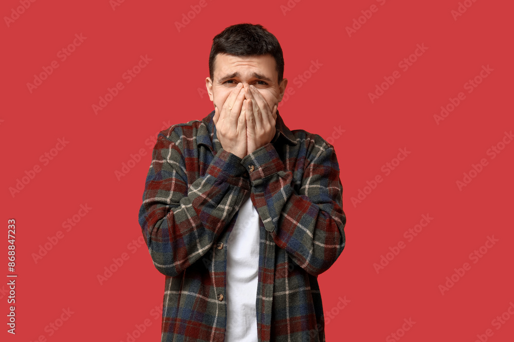 Handsome young man feeling bad smell on red background Handsome young man feeling bad smell on red background