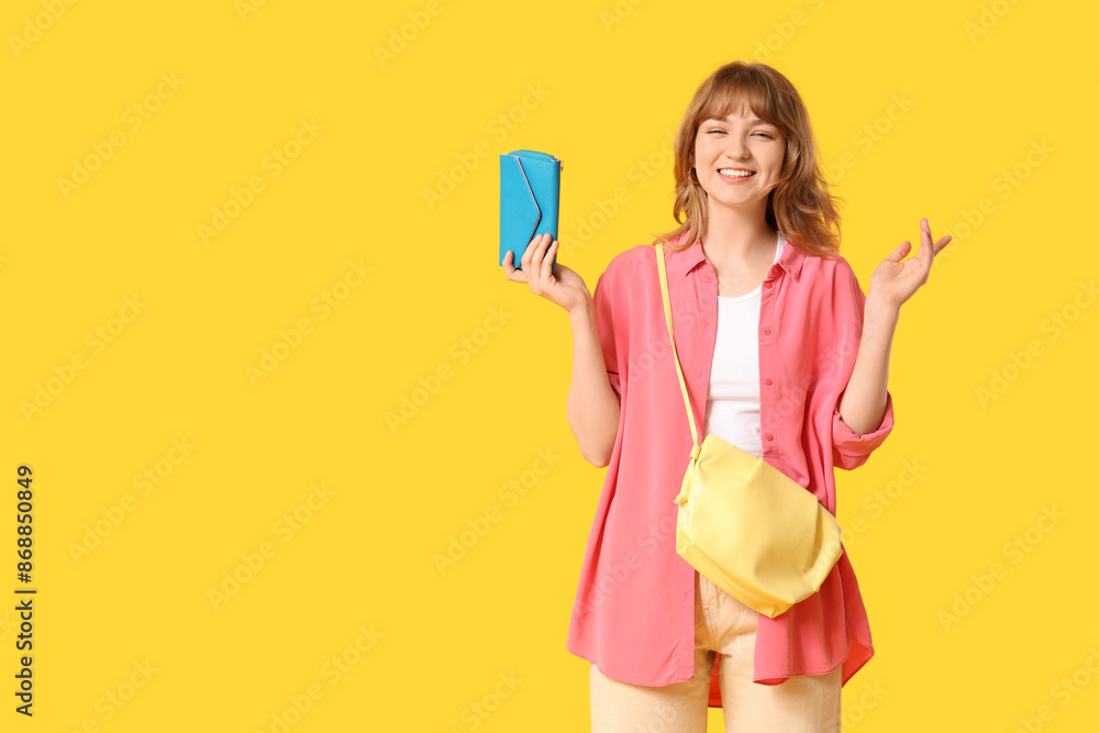 Beautiful young woman holding blue wallet on yellow background Beautiful young woman holding blue wallet on yellow background