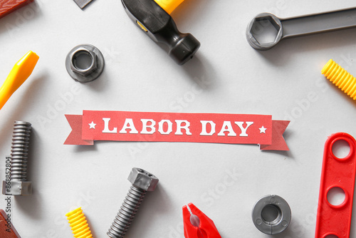 Ribbon with text LABOR DAY and toy tools on white background. Labor Day celebration