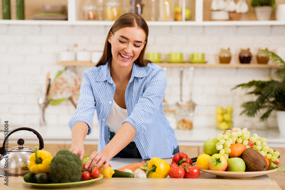 A woman smiles as she arranges fresh produce on a plate in her kitchen. A woman smiles as she arranges fresh produce on a plate in her kitchen.