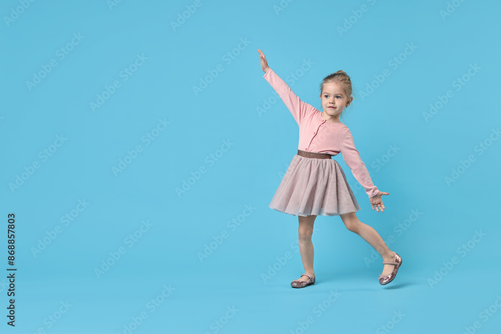 Cute little girl dancing on light blue background, space for text Cute little girl dancing on light blue background, space for text