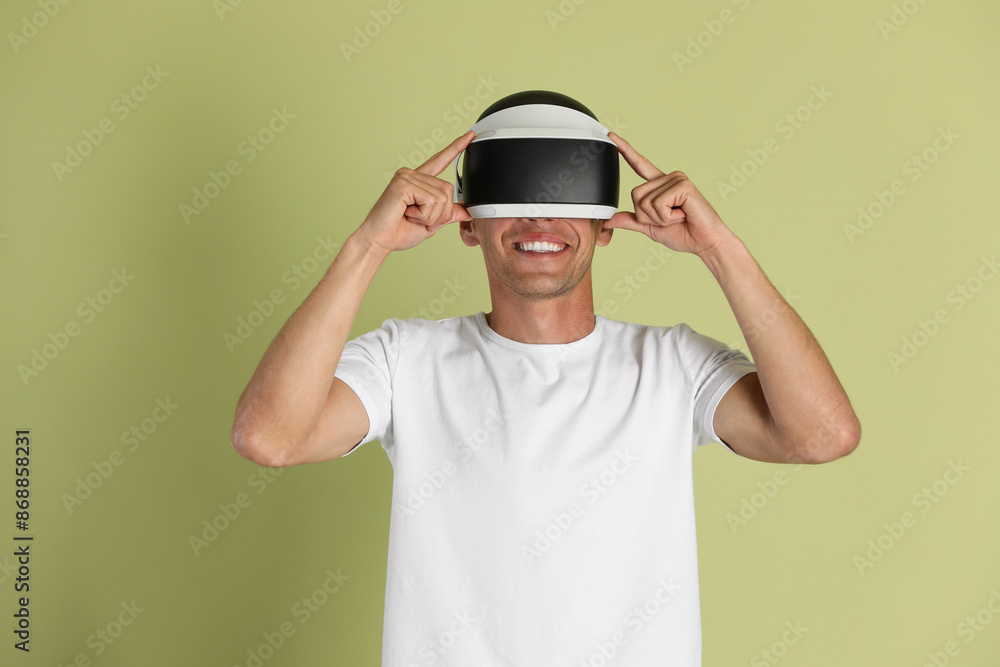 Smiling man using virtual reality headset on light green background Smiling man using virtual reality headset on light green background