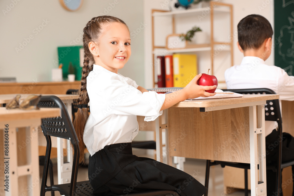 Little schoolgirl with apple at desk in classroom Little schoolgirl with apple at desk in classroom