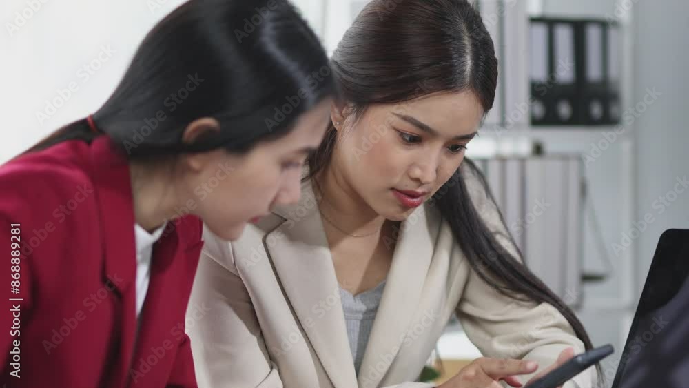 Happy Asian businesswoman in office talking with coworkers while playing on mobile phone. Happy Asian businesswoman in office talking with coworkers while playing on mobile phone.
