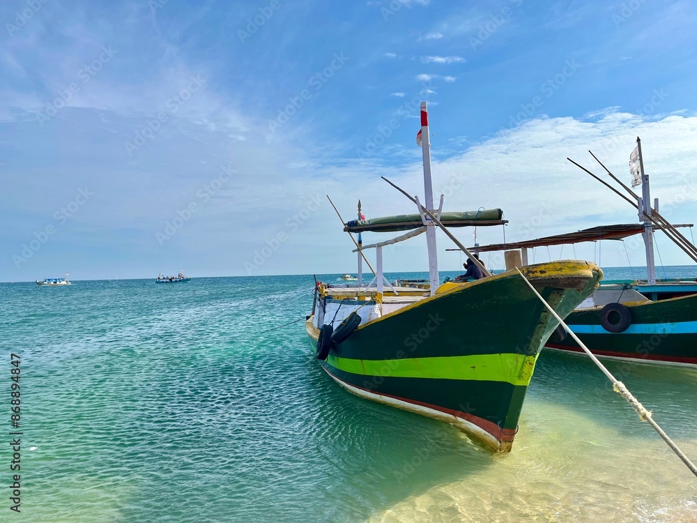 Several traditional wooden fishing and passenger boats moored on the beautiful beach in Gili Ketapang, Indonesia Several traditional wooden fishing and passenger boats moored on the beautiful beach in Gili Ketapang, Indonesia